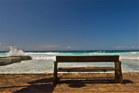 An empty wooden bench facing the ocean in Tenerife